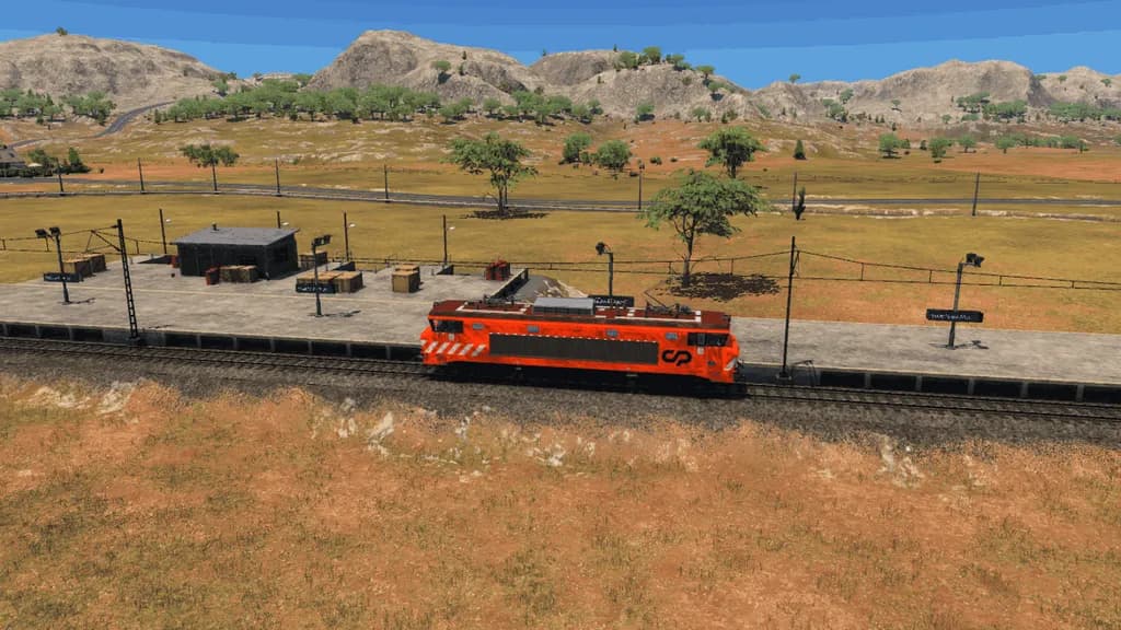 Locomotiva elétrica CP 2600 cor de laranja numa estação, numa paisagem seca com montanhas